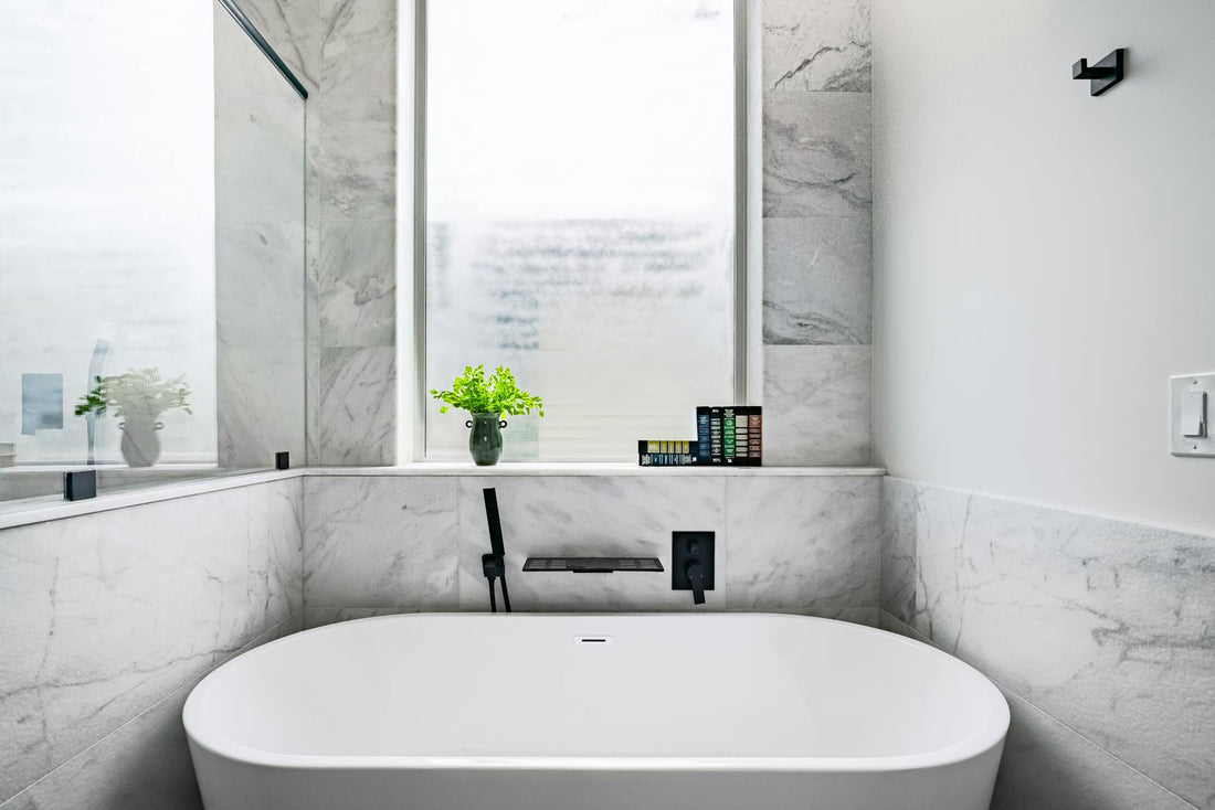 Luxurious marble bathroom featuring a stylish white bathtub and minimalist decor.