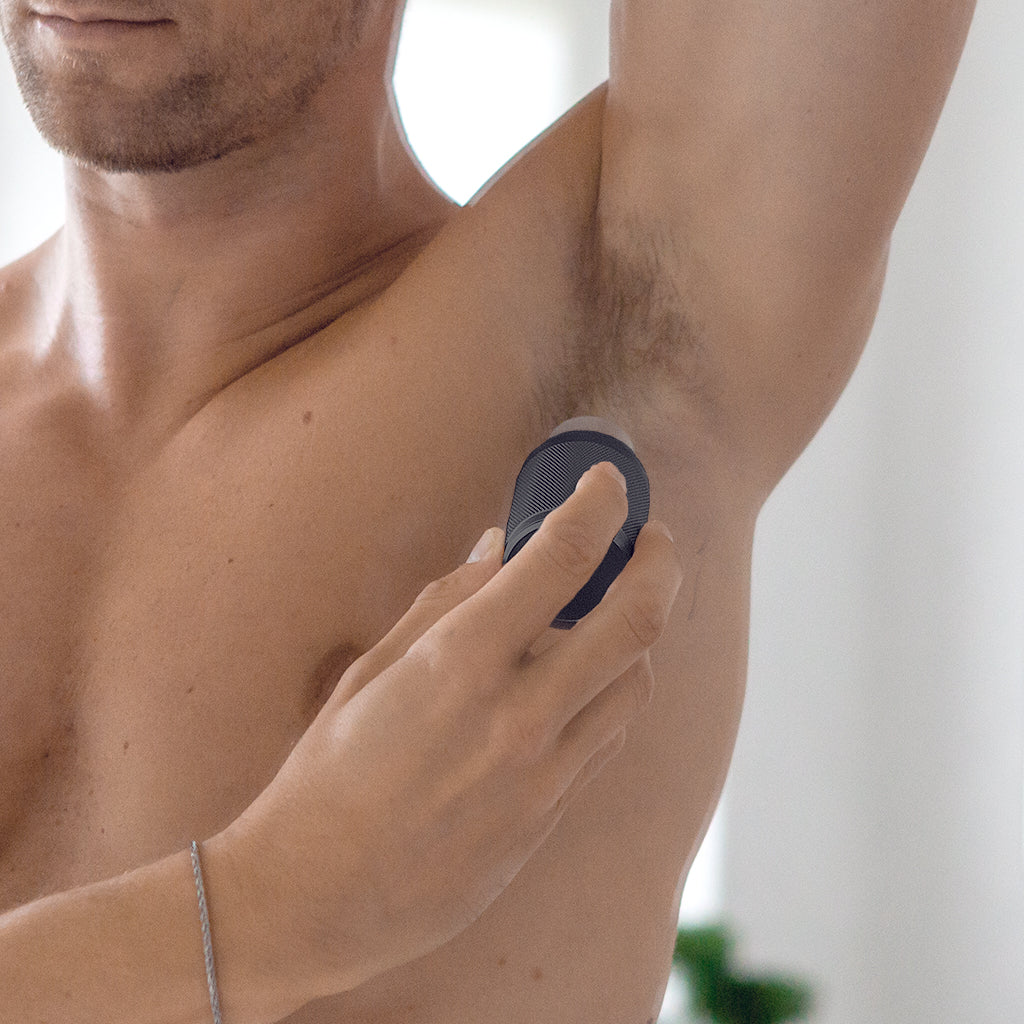 Male applying deodorant on his armpit. The deodorant i dark. 